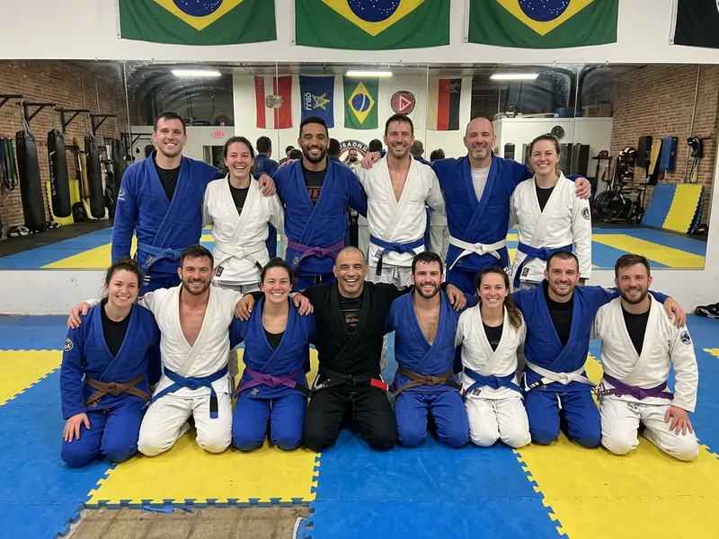 Grupo de jiu jitsu con kimono y su profesor reunidos en el tatami después del entrenamiento