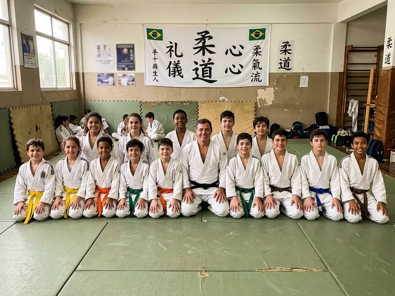 Foto de fim de aula de uma turma de judô infantil ajoelhada no tatame com o sensei