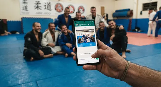 Mão segurando celular enviando uma foto da turma no tatame