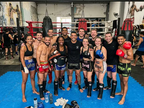 Alunos de muay thai com luvas reunidos no ringue da academia